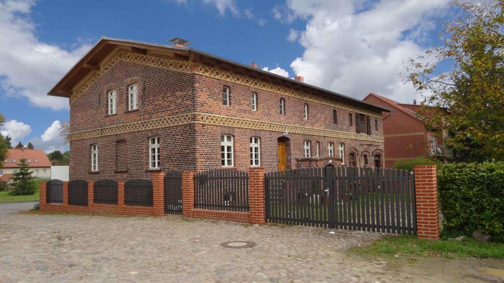 ein Backsteingebäude mit einem Zaun davor in der Unterkunft Nitschke "Zum Nusshof" in Ahrensfelde
