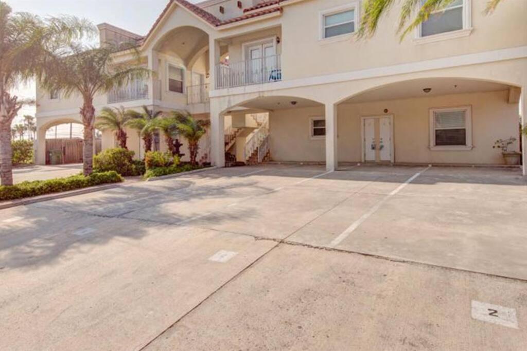 een groot huis met palmbomen en een oprit bij 1st Floor 2 Bed 2 Bath Condo w Pool By Beach in South Padre Island