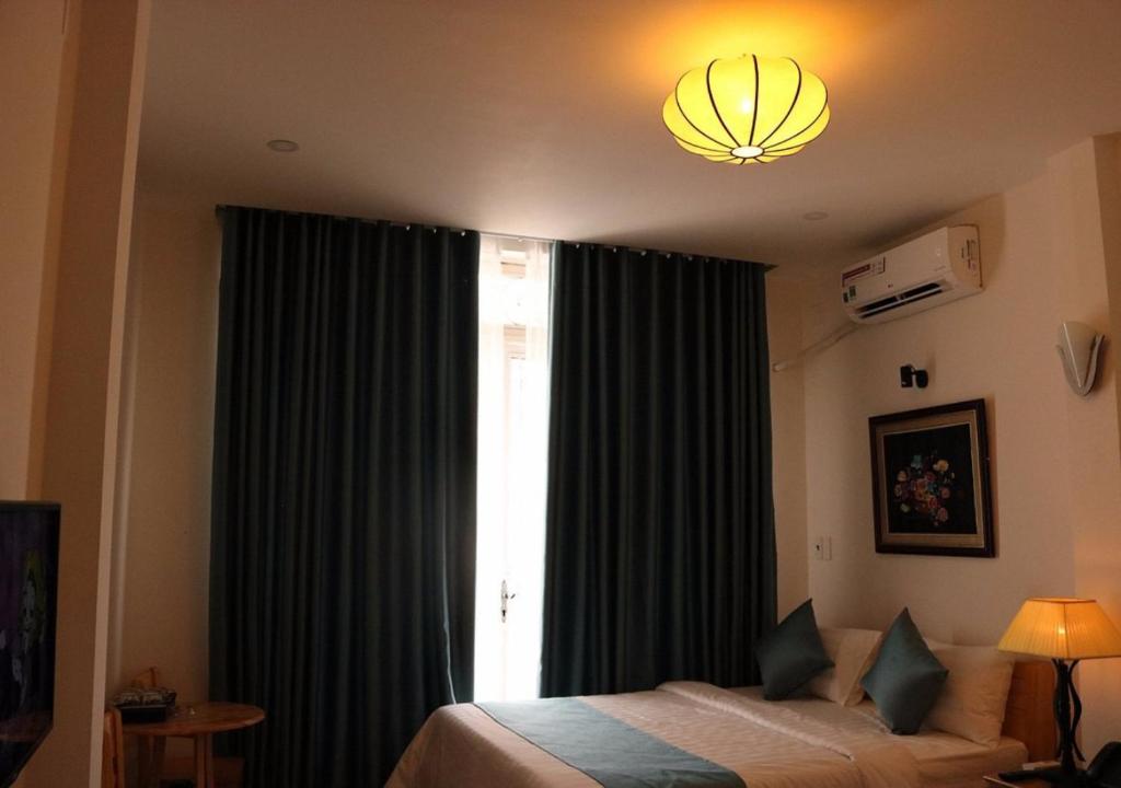 a bedroom with a bed and a window with curtains at Saigoneer Hotel in Ho Chi Minh City