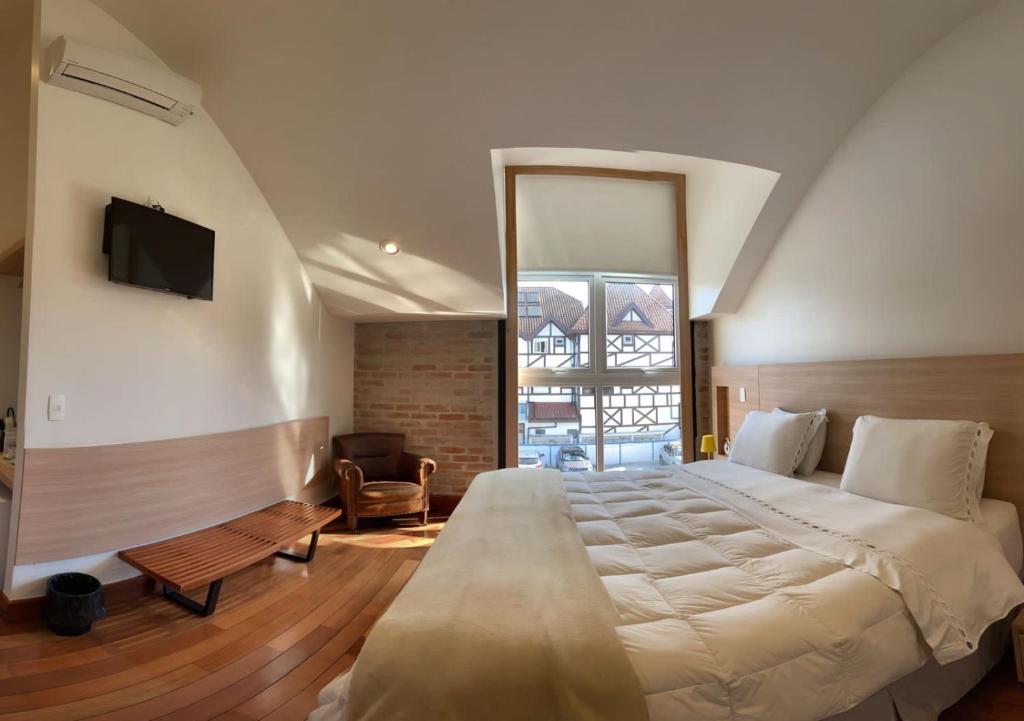 1 dormitorio con 1 cama grande y TV en Austin Suites, en Campos do Jordão