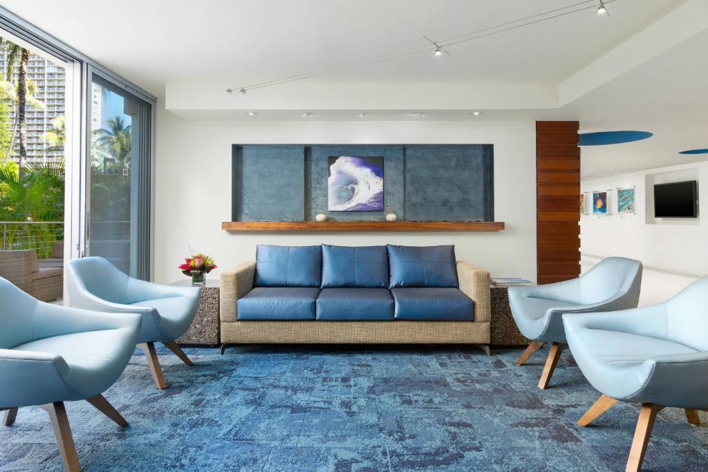 a living room with a blue couch and chairs at Courtyard by Marriott Waikiki Beach in Honolulu