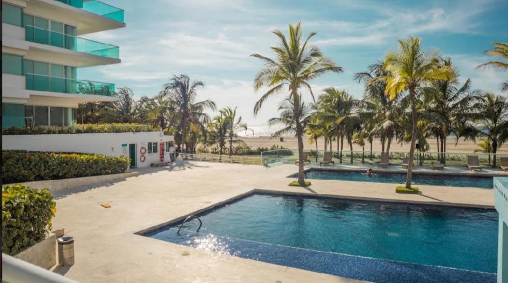 een zwembad met palmbomen en een gebouw bij Cartagena Beach Apartment - Salida Directa Al Mar in Cartagena