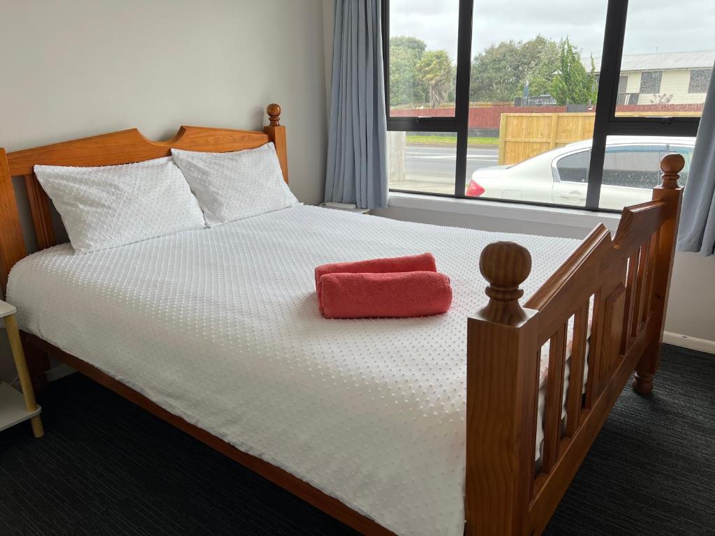 a bedroom with a bed with a red pillow on it at Yucca Home in Auckland