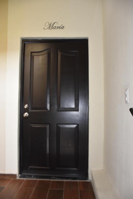 Una puerta negra en una pared blanca con un cartel. en Departamento María. La Crucecita Huatulco., en Santa Cruz Huatulco