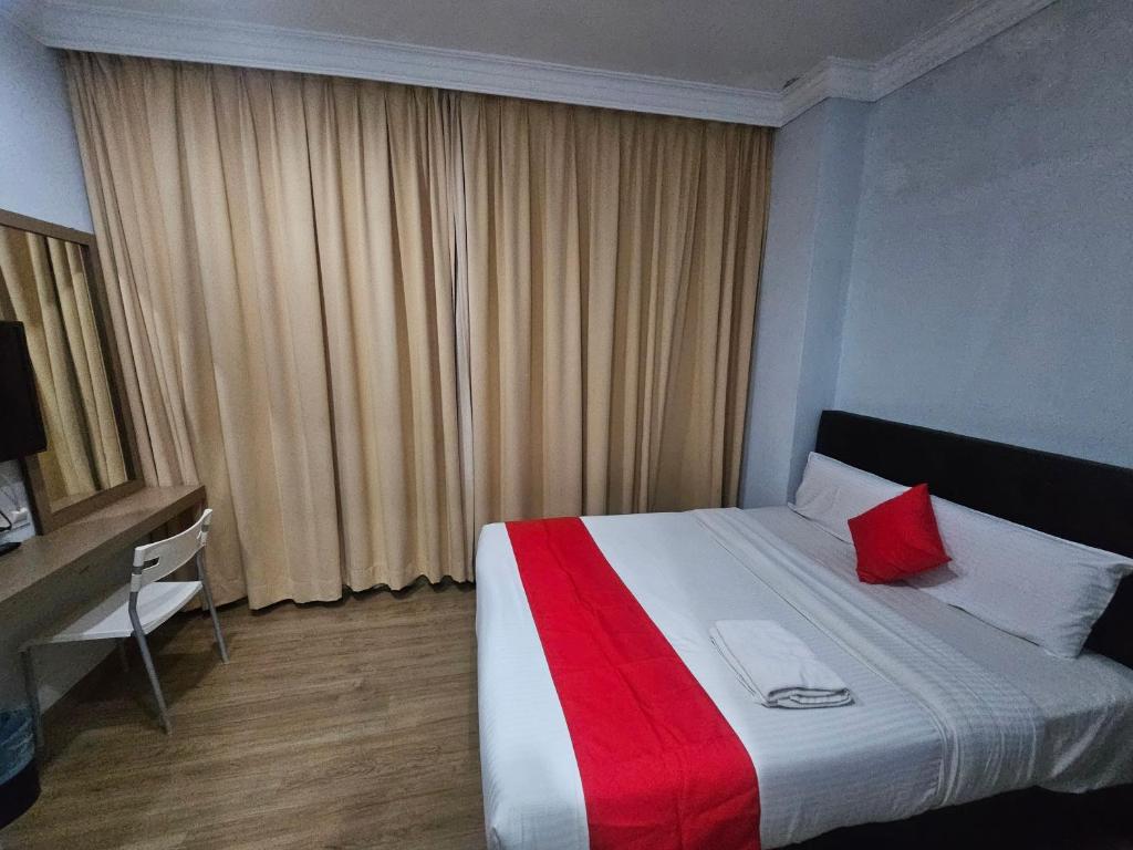 a bedroom with a bed with a red and white blanket at CHARISMA HOTEL in Kuantan