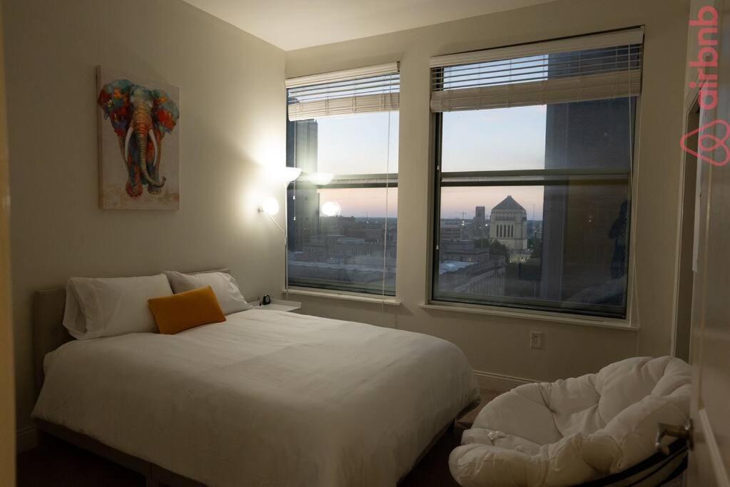 een slaapkamer met een wit bed en 2 ramen bij Luxurious 2 Bedroom Downtown City Views! in Indianapolis