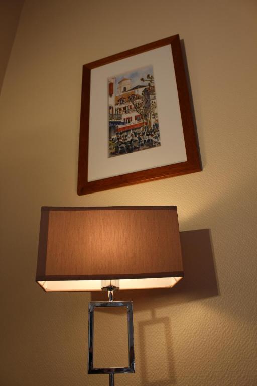 a close up of a lamp with a picture on the wall at Hotel Bel Air in Saint-Jean-de-Luz