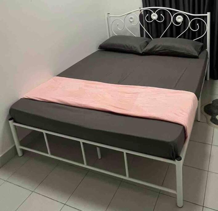 a bed with a black frame and a pink blanket at Afrinas Homestay @ Banting in Banting