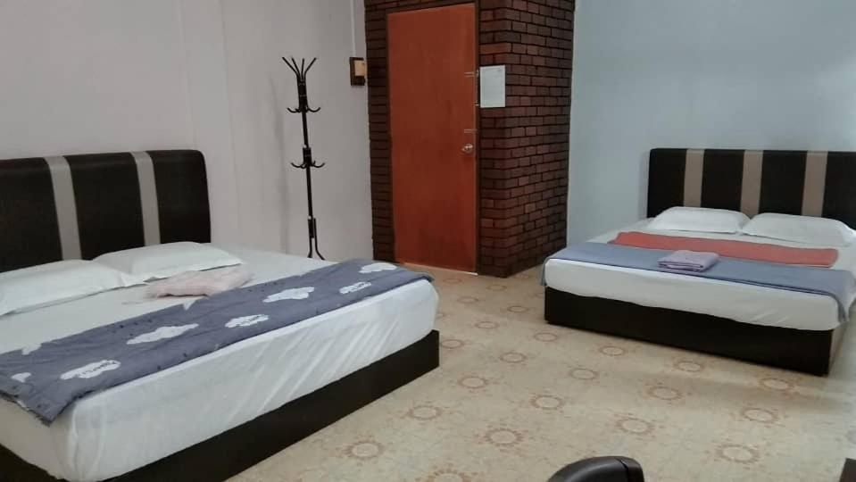 um quarto com 2 camas e uma porta vermelha em Happy Bentong Guest House em Bentong