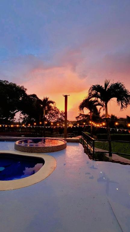 San José的住宿－Quinta El Molino，棕榈树背景的游泳池享有日落美景