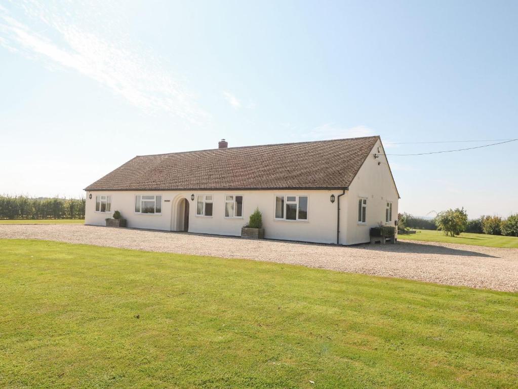 une maison blanche avec une grande pelouse dans l'établissement The Clealings, à Witney