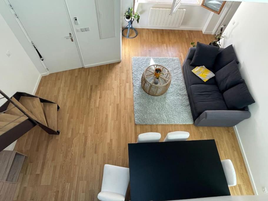 sala de estar con sofá negro y sillas blancas en Appartement moderne, en Saint-Vallier