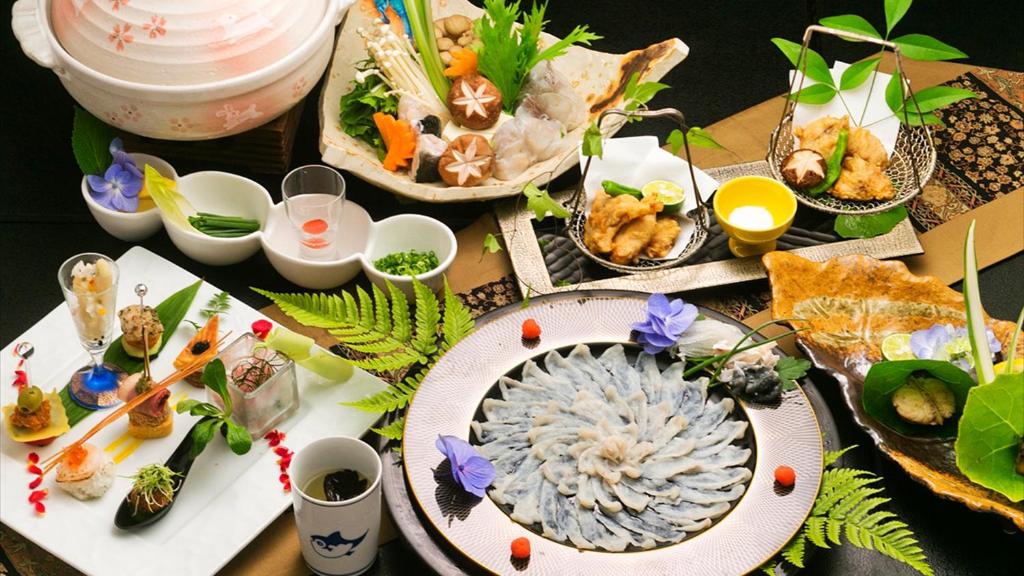 uma mesa com muitos pratos de comida em 夕景の宿　海のゆりかご　萩小町 em Hagi