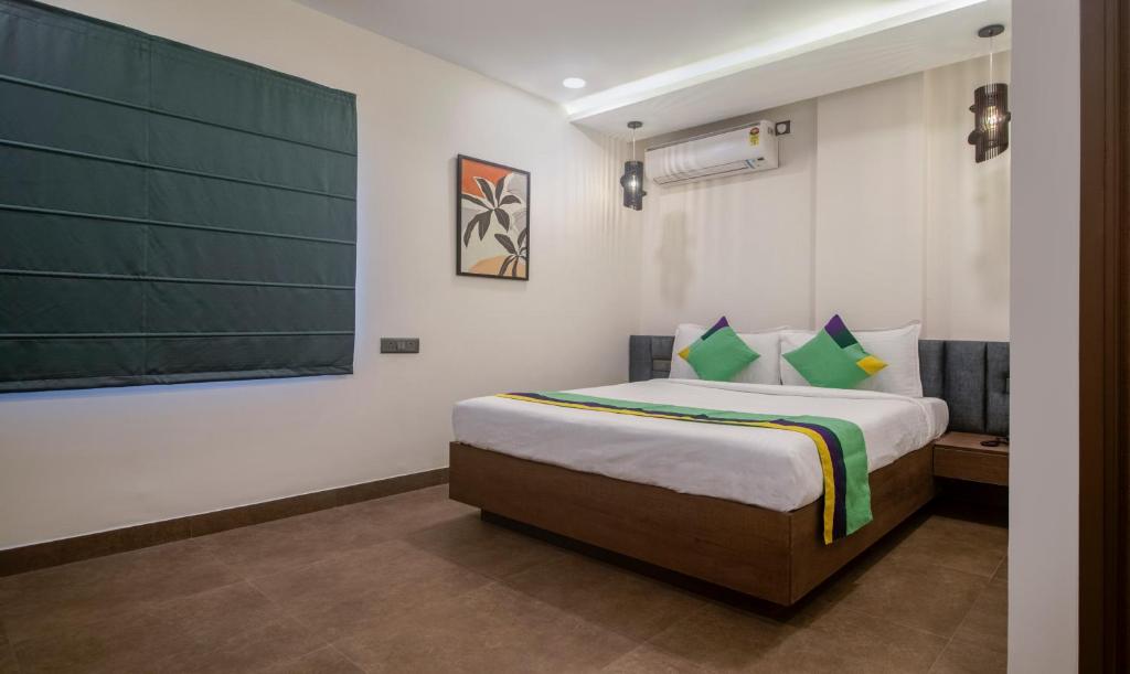 Treebo Trend The Rise في حيدر أباد: غرفة نوم مع سرير وطاولة خضراء على الحائط