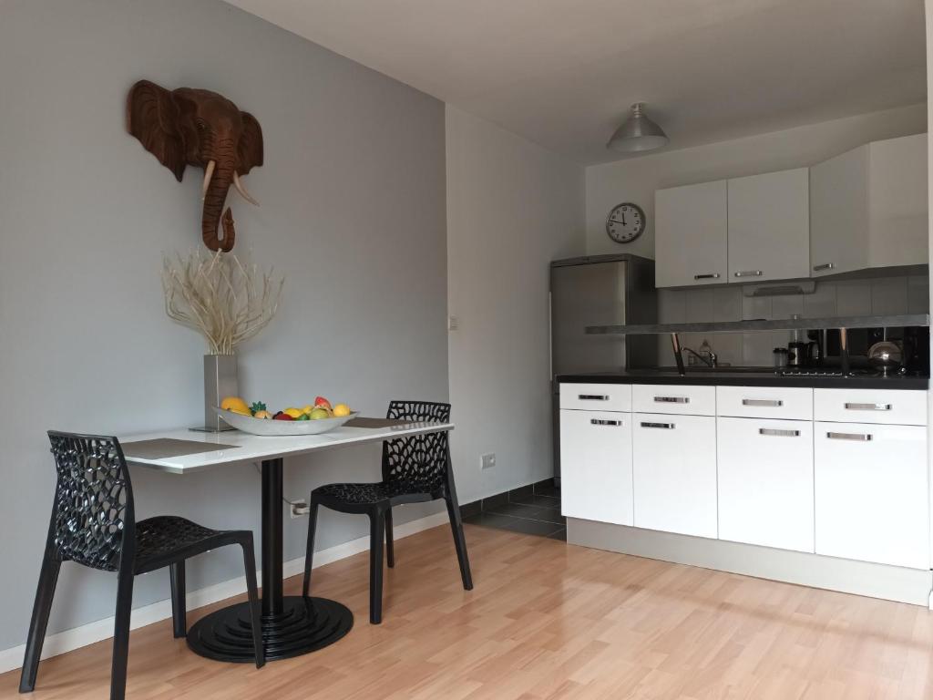 a kitchen with a table and chairs and a kitchen with white cabinets at résidence la clairière aux portes de la baie de Somme in Abbeville