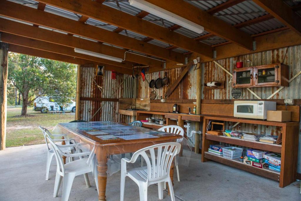 a dining room with a table and white chairs at Gertrude Gypsy Wagon River Heads in River Heads
