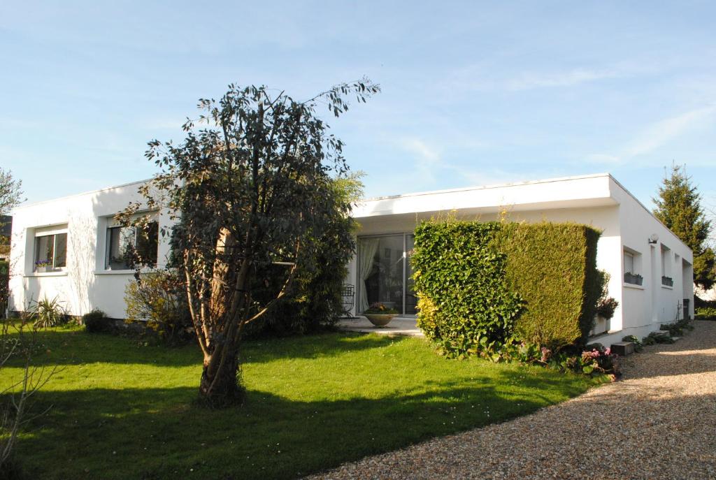 una casa blanca con un árbol en el patio en Chambres d'hôtes La Tribu en Quévreville-la-Poterie