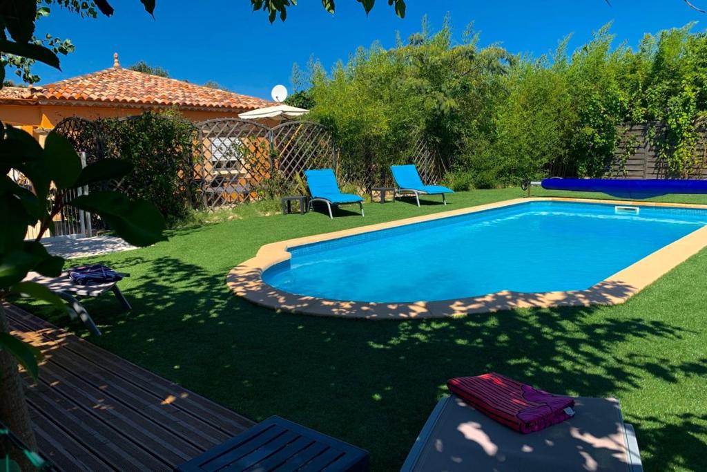 - une piscine dans une cour avec 2 chaises bleues dans l'établissement LAcacia, à Plaissan