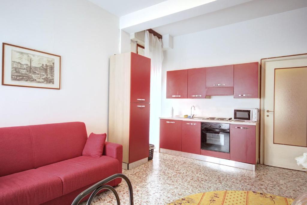 a living room with a red couch and a kitchen at MilanRentals - Teodorico Apartment in Milan