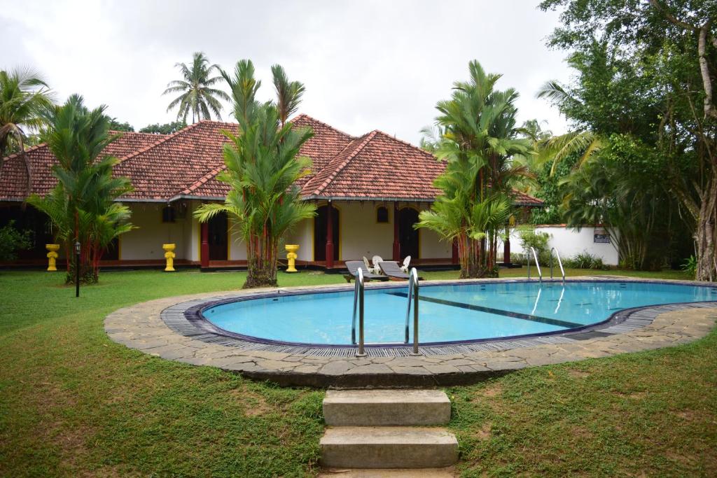 een zwembad voor een huis met palmbomen bij Nick Villa - Bentota in Bentota