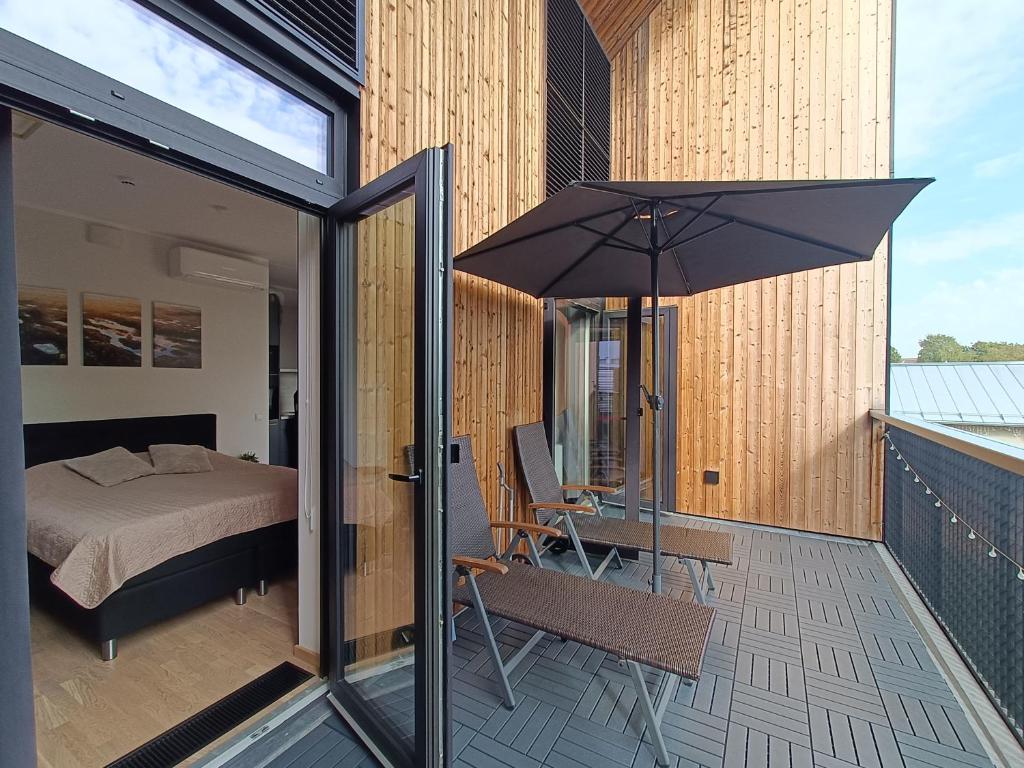 a bedroom with a bed and an umbrella on a balcony at Stiilne ja avar kodu Tartus, Riia 20 in Tartu