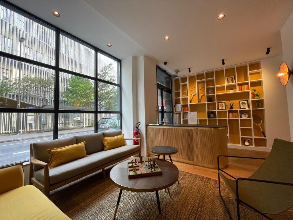 a living room with a couch and a table at Parici Hôtel Boulogne Billancourt in Boulogne-Billancourt