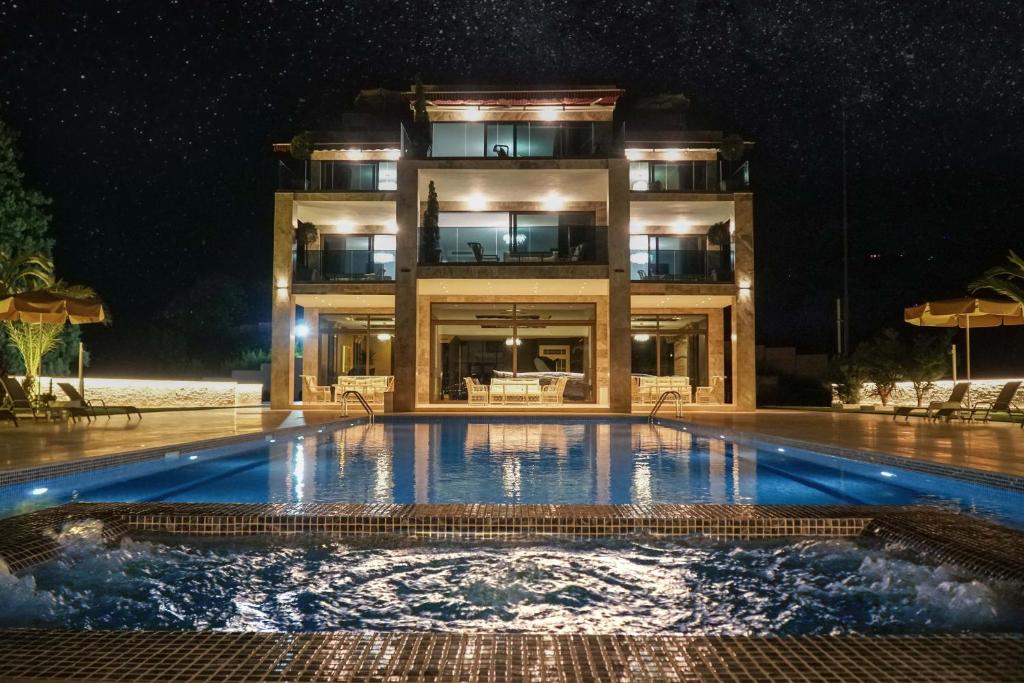a swimming pool in front of a building at night at Villa Elysium Park & SPA in Batumi