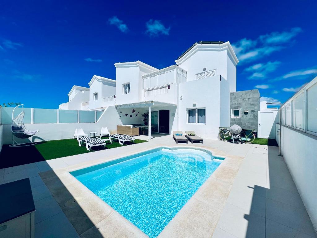 una casa blanca con piscina frente a ella en Lovely Villa Sanmar, heated pool, en Playa Blanca