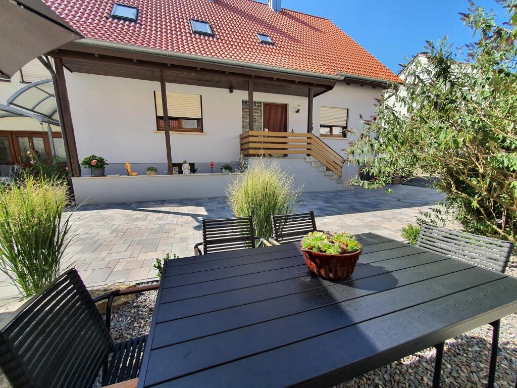 a wooden table in front of a house at Gemütliches Ferienhaus in Schnaid mit zwei separaten und geräumigen Wohnungen - ausgestattet mit je einer großen Küche, zwei Schlafzimmern und einem Badezimmer in Hallerndorf