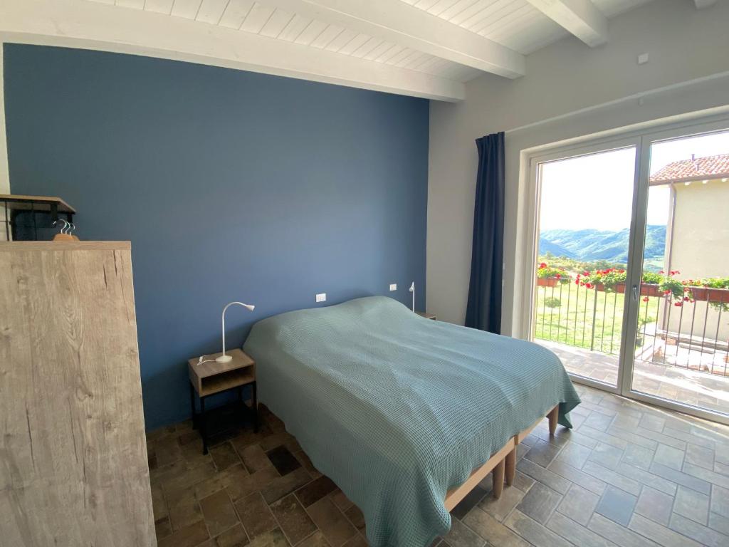 a blue bedroom with a bed and a large window at Fuoridicampo in Roncovetro