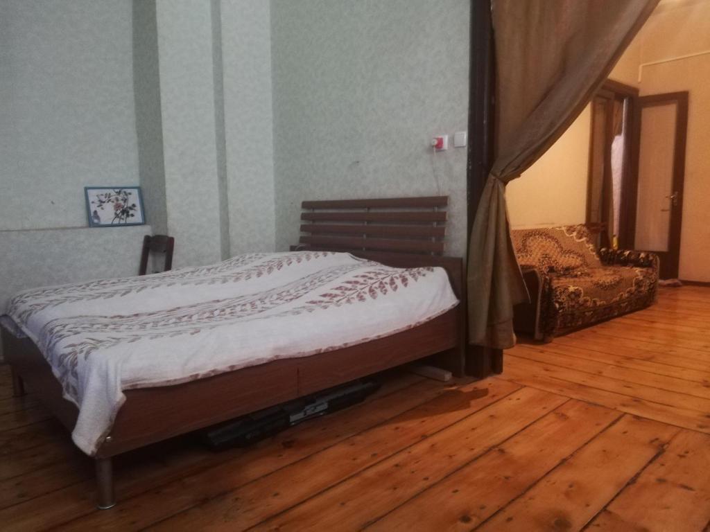 Bett in einem Zimmer mit Holzboden in der Unterkunft квартира in Tbilisi City