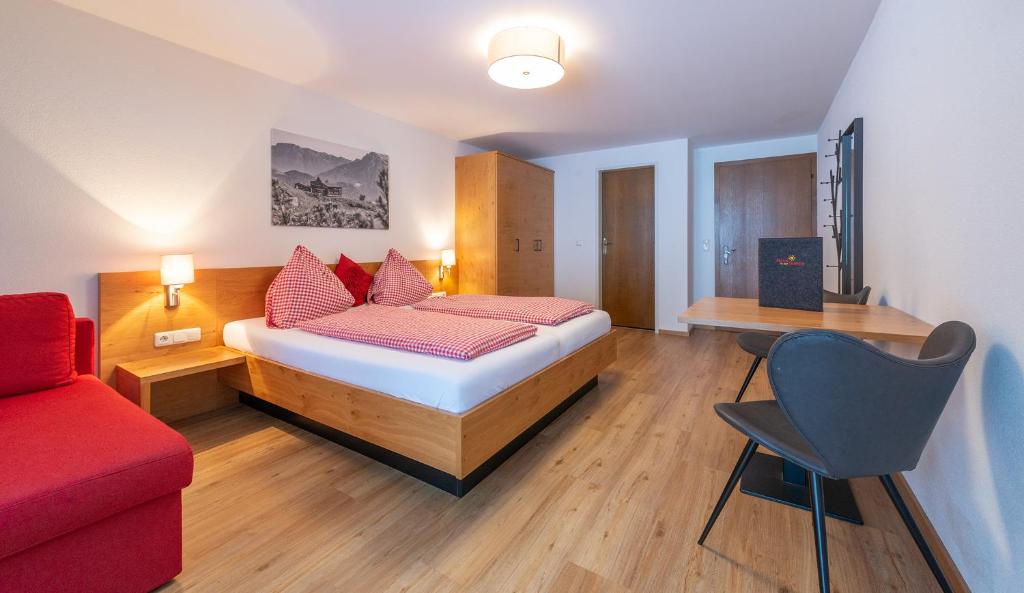 a bedroom with a bed and a red chair at Pension Haus in der Sonne in Fieberbrunn