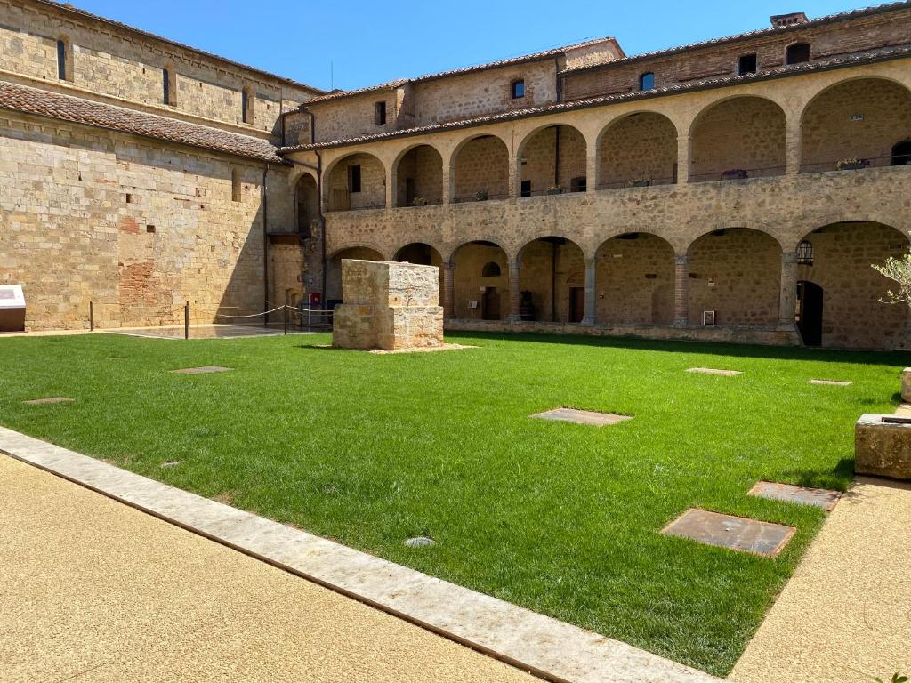 a courtyard of an old building with green grass at Ostello Contessa Ava dei Lambardi in Monteriggioni