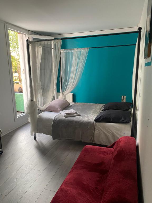 - une chambre avec un lit aux murs bleus et une fenêtre dans l'établissement Cosy room chez l'habitant, à Montigny-le-Bretonneux