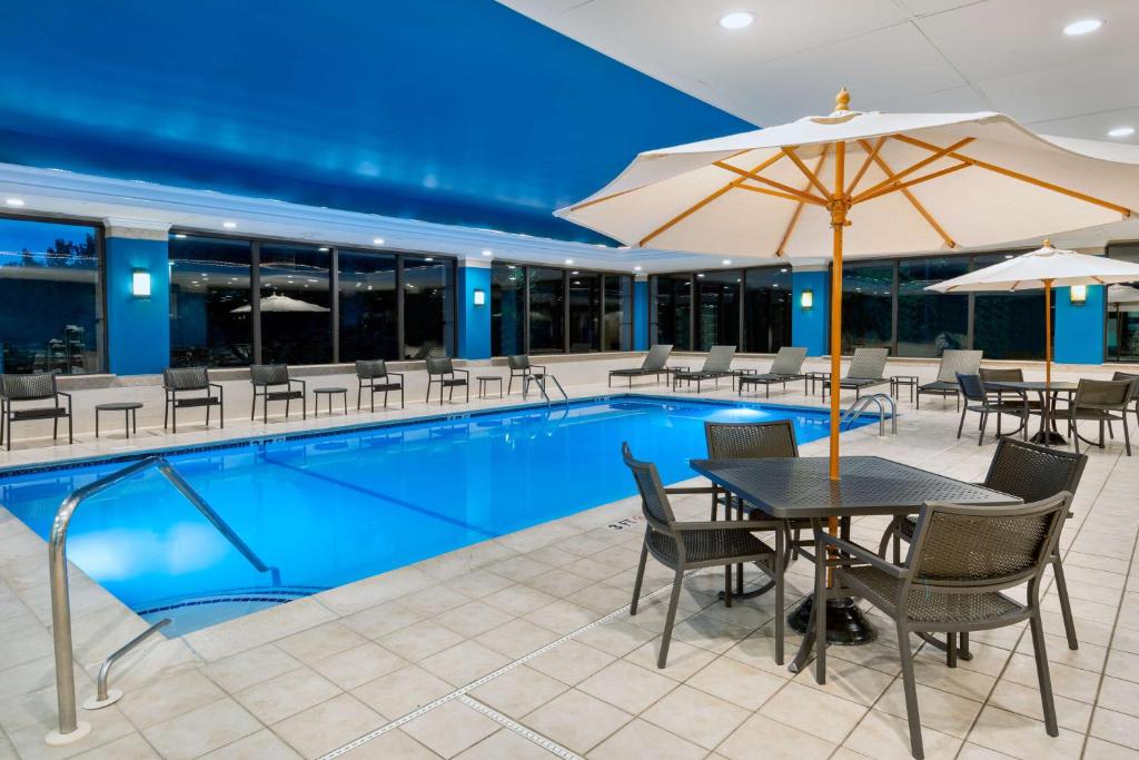 a pool with a table and chairs and an umbrella at Hampton Inn Hartford Airport in Windsor Locks