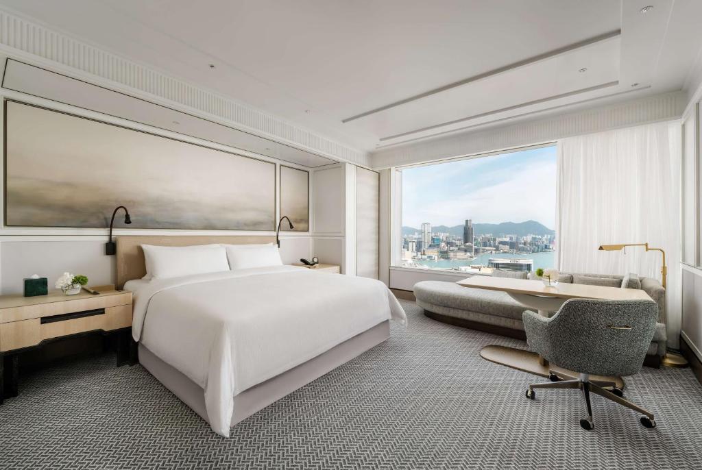 a bedroom with a large white bed and a desk and a window at Island Shangri-La, Hong Kong in Hong Kong
