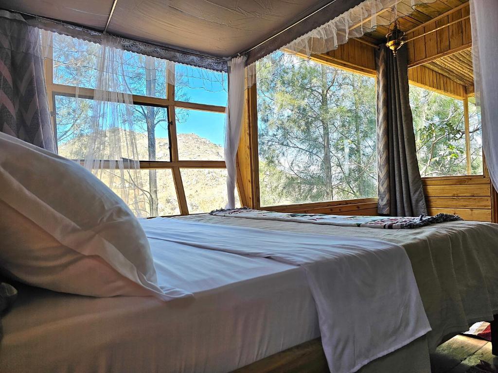 a bed in a room with a large window at Jabali Mountain Cabin in Iringa