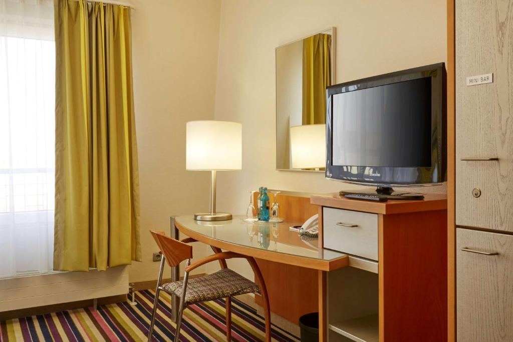 a hotel room with a desk with a television on it at H+ Hotel Köln Hürth in Hürth