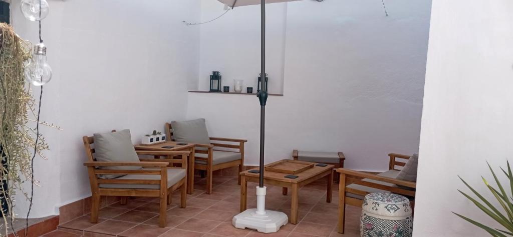 ein Restaurant mit Holztischen, Stühlen und einem Sonnenschirm in der Unterkunft Casa Rural Olivares in Villanueva de Algaidas