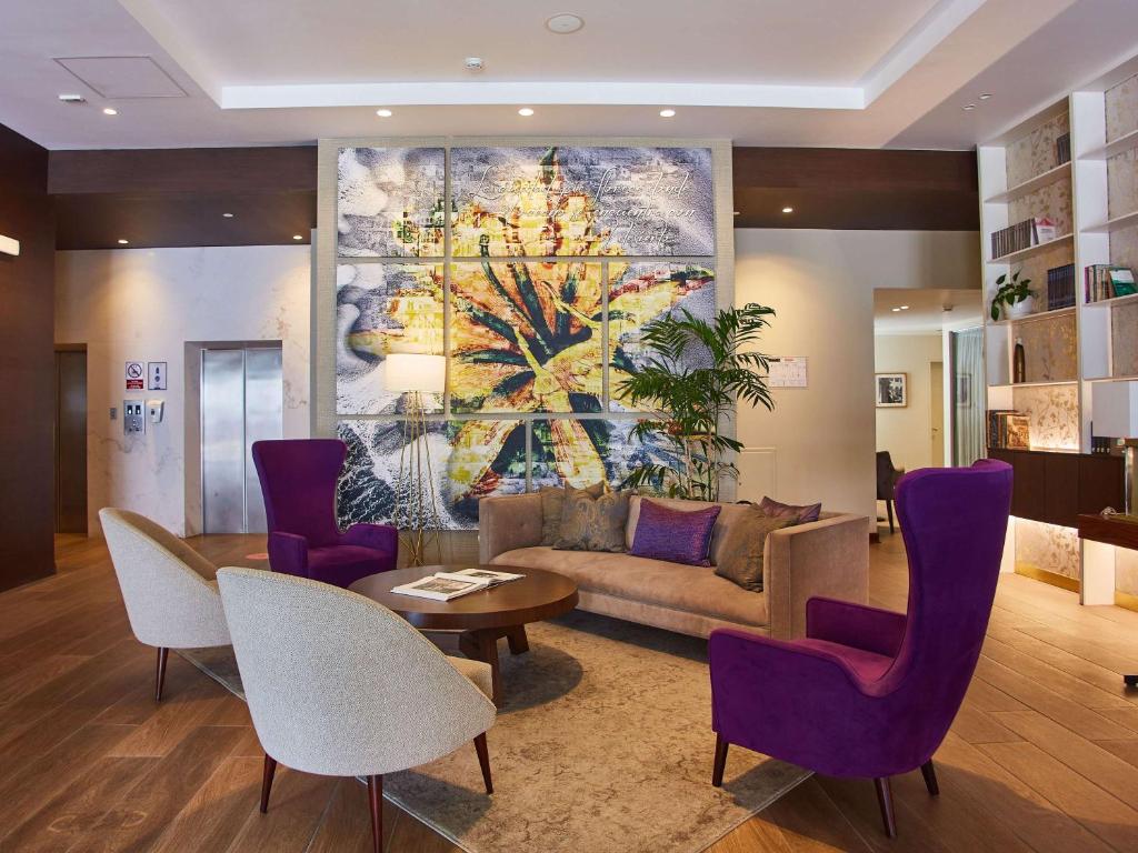 a living room with a couch and a table and purple chairs at Manto Hotel Lima - MGallery in Lima