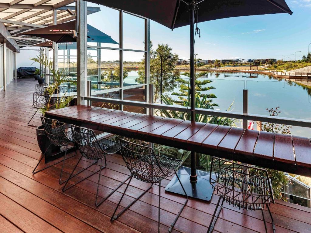 uma varanda com uma mesa e cadeiras de madeira e uma piscina em Mercure Sunshine Coast Kawana Waters em Kawana Waters