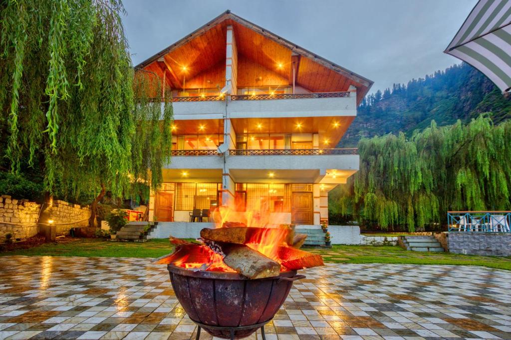 a large building with a fire pit in front of it at Solang Cottage By Snow City Farm in Palchān