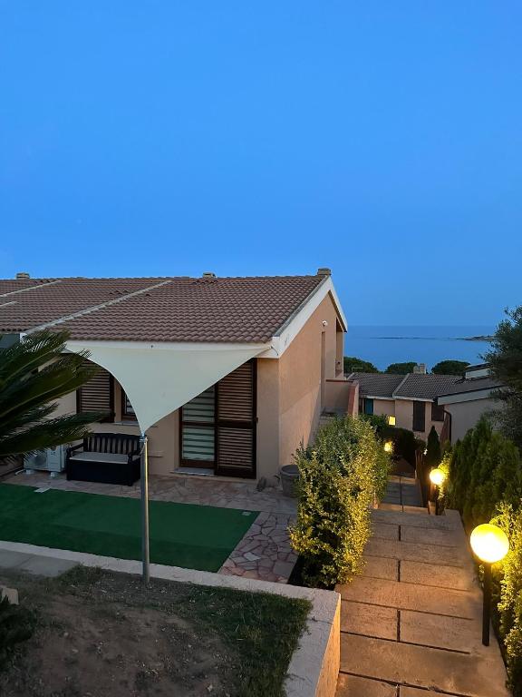 a house with a white umbrella in a yard at Villa Elma in Villaputzu