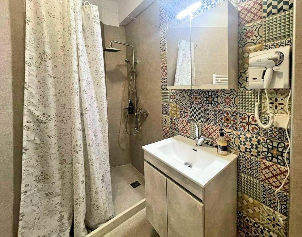 baño con lavabo y cortina de ducha en Varsamos, en Yiannioú