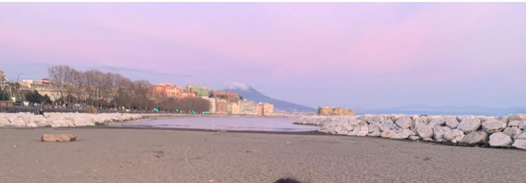 a beach with a rock wall and the water at A Un Passo Da Tutto... in Naples