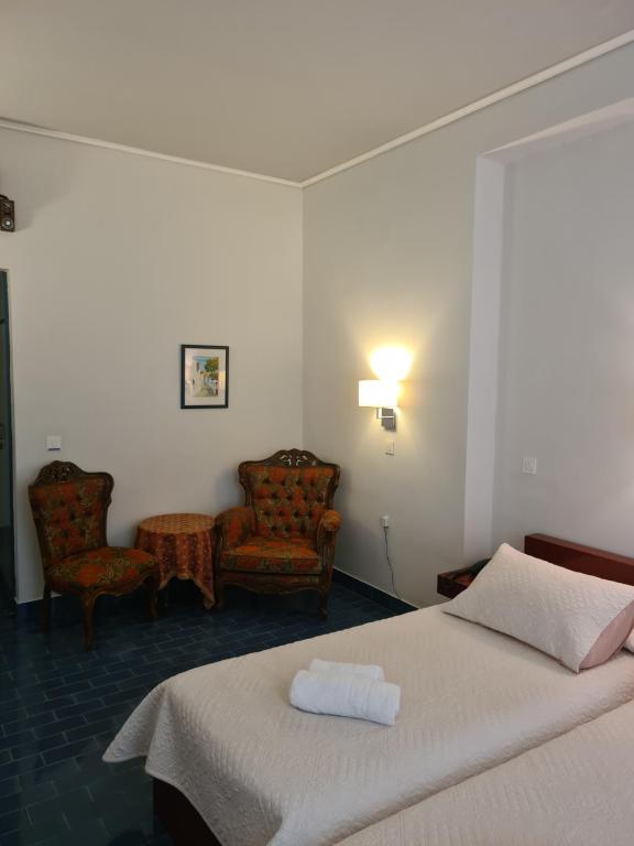 um quarto de hotel com uma cama e duas cadeiras em Greco Hotel em Hydra