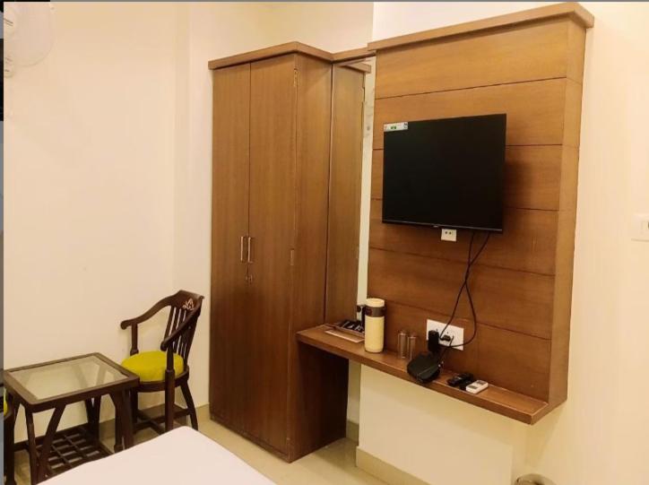 um quarto com um armário de madeira com uma televisão em Hotel Sakshi Inn Rooms and Restaurant em Gwalior