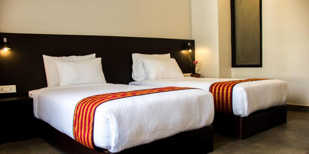 una camera con due letti con lenzuola bianche e strisce arancioni di Hotel Bhutan Ga Me Ga a Phuntsholing
