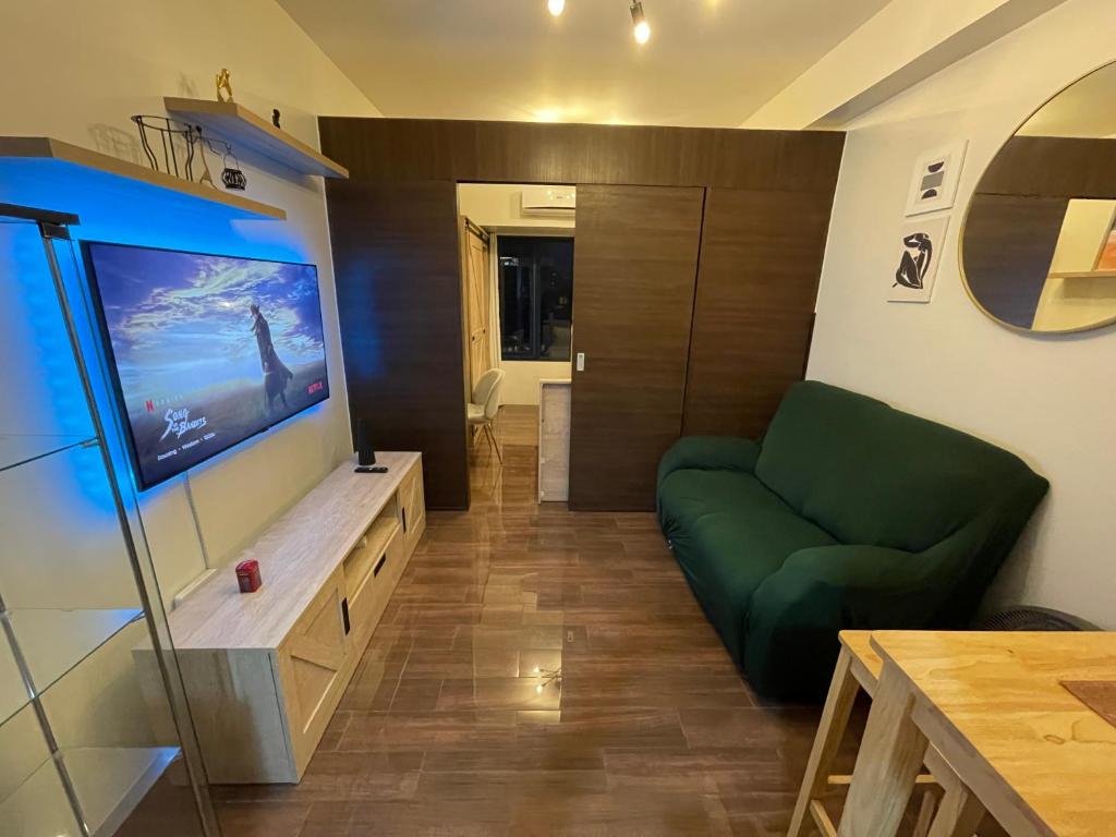 un soggiorno con divano verde e TV a schermo piatto di Destina Stays, Cozy & Netflix @Air Residences, Makati, Metro Manila a Manila
