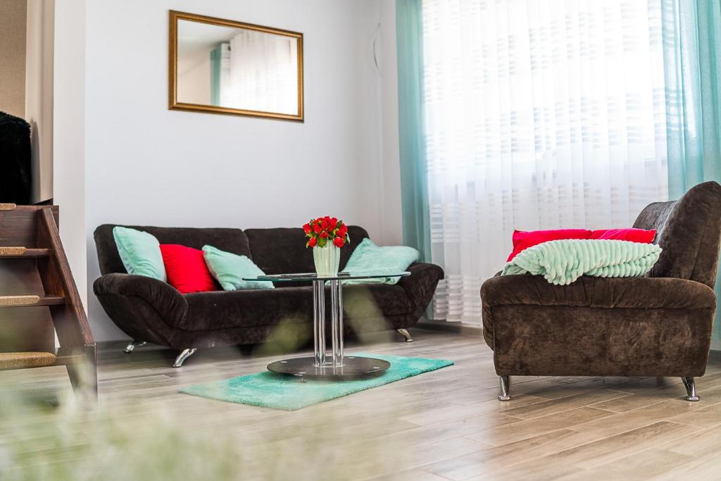 ein Wohnzimmer mit 2 Sofas und einem Tisch mit Blumen in der Unterkunft Emilia domki U Przyjaciół in Żarnowska